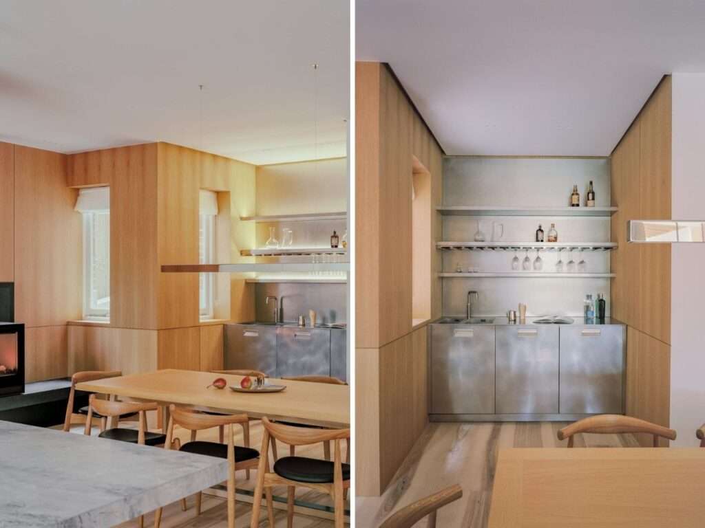 Split view of a sleek stainless steel bar and kitchenette alcove adjacent to a wooden dining area with a fireplace.