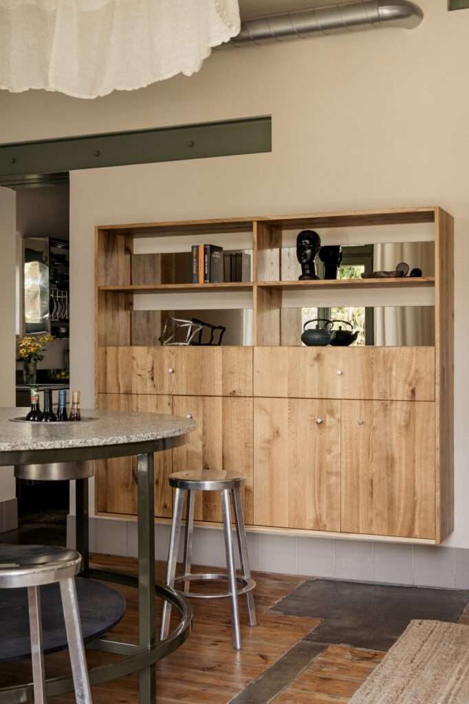 Built-in oak wooden shelving unit in P81 House with mirror inserts and raw steel structural details.