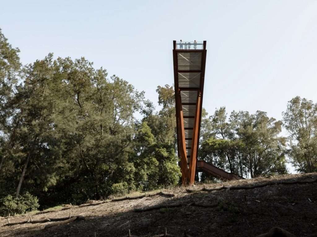 Low-angle view of the tall V-shaped steel supports of the lookout platform reaching up from the hillside.