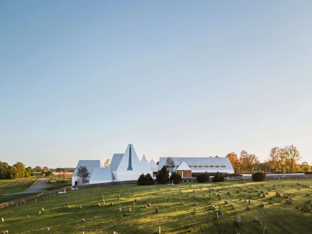 Eye-level view of The Lost Shtetl Museum from the cemetery side, showing the textured aluminum panels and the irregular peaks of the roof.