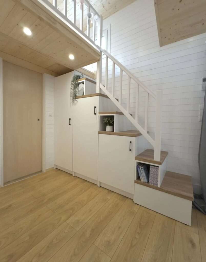 Close-up of white storage cabinets built into the staircase of a tiny home.