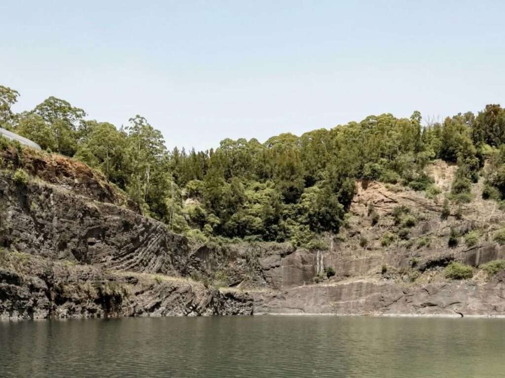 Wide view of the Hornsby Quarry rock faces and a deep water pool at the bottom of the valley.