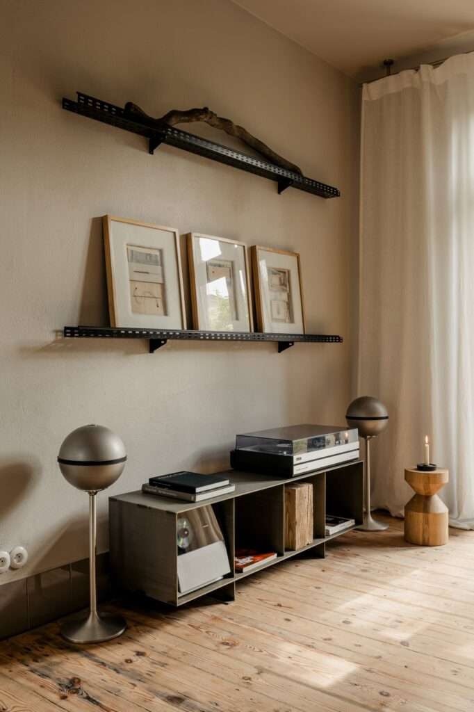Interior detail of P81 House showing a record player on a steel console and wall-mounted industrial metal shelves holding artwork.