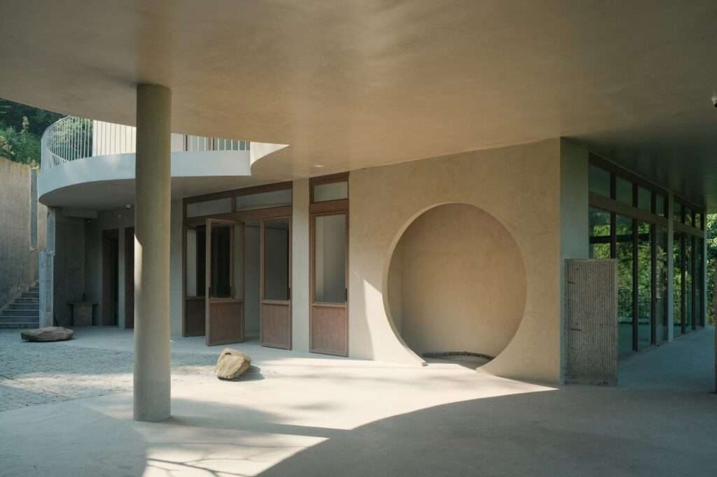 A view from under the concrete slab canopy showing the interaction between the built structure and the mountain foliage.