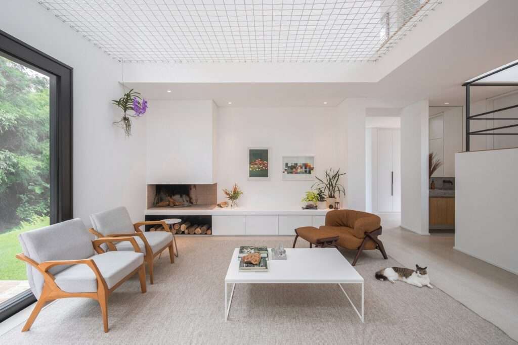 Bright minimalist living room featuring a double-height ceiling integrated with a suspended lounge net.
