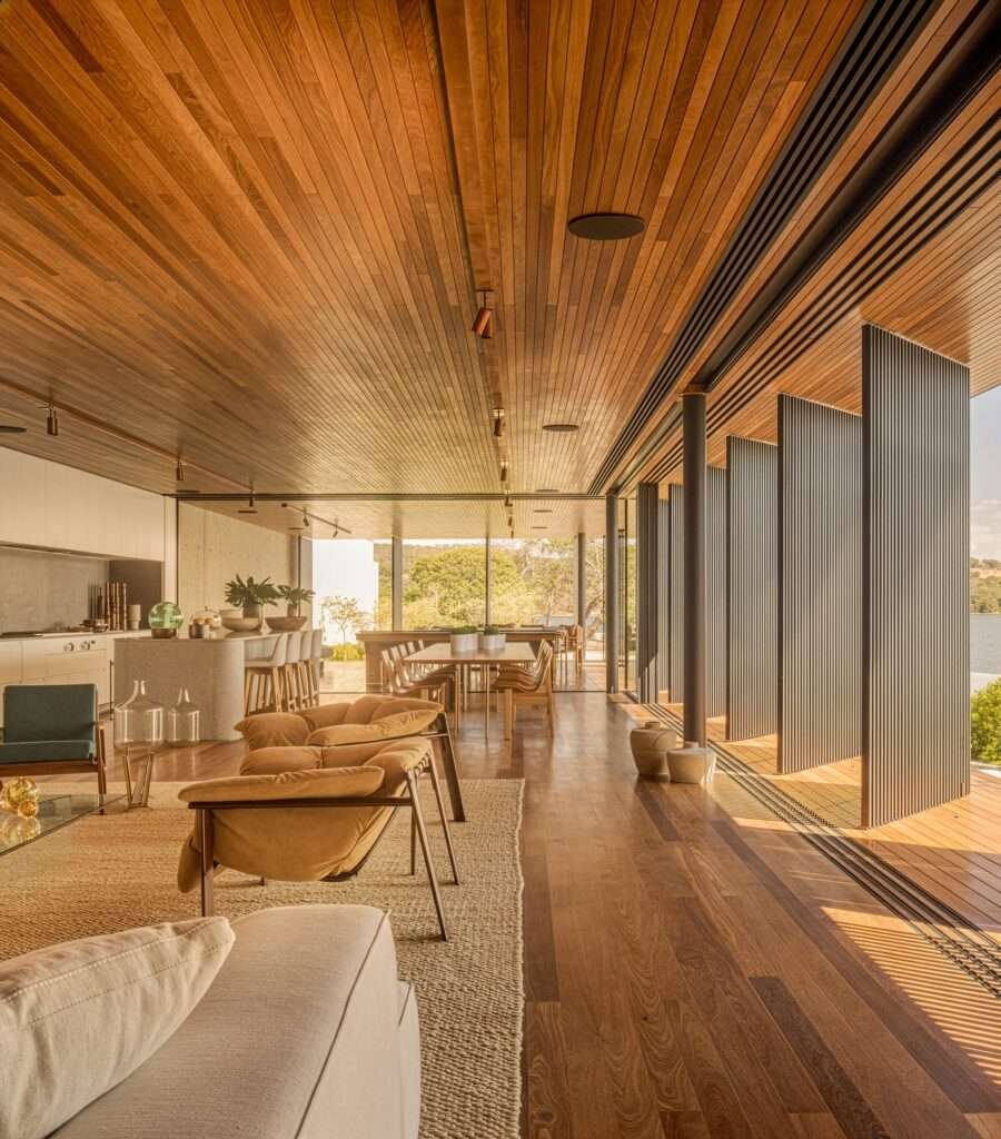 Interior perspective showing a long wood-clad corridor looking out towards a concrete staircase and garden.