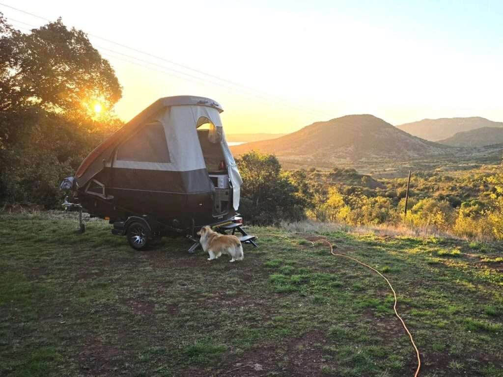 Dashaway ECT trailer with the roof raised to 6 feet, parked on a hill overlooking a valley at sunset.