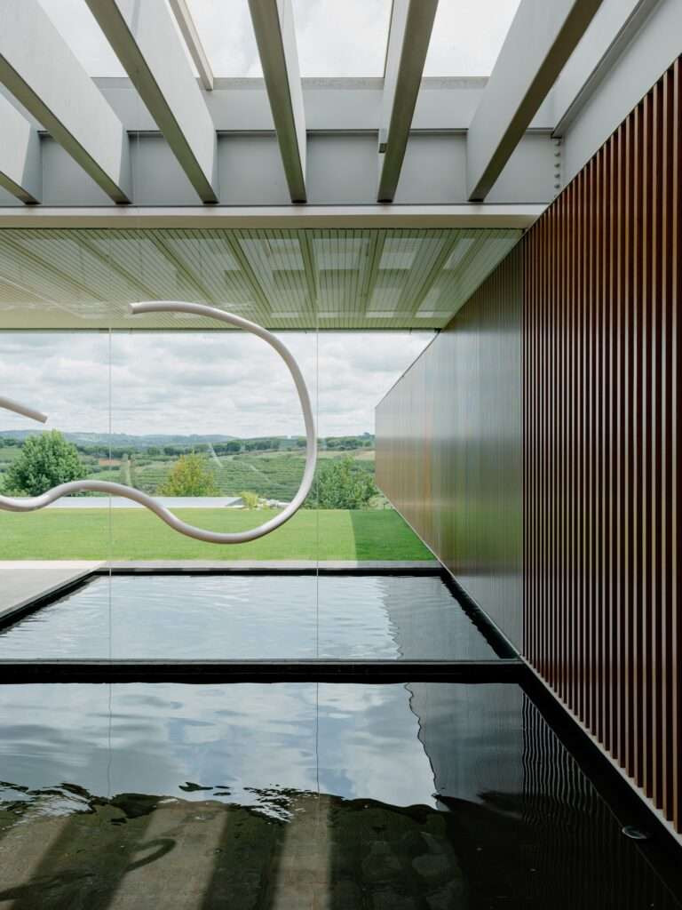 View from the interior courtyard through a glass partition toward the rolling green hills and landscape of Bragança Paulista.
