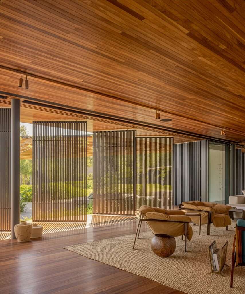 A modern living room with wood surfaces, a large area rug, and rotating slatted wood panels.