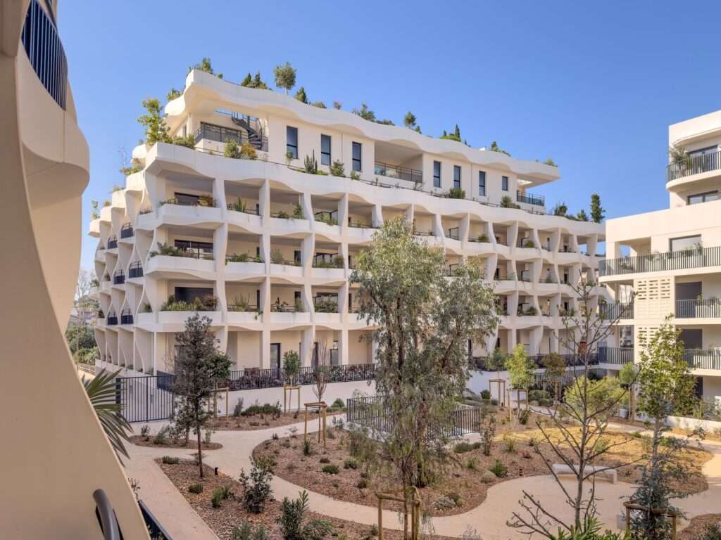 Wide shot of the Secret Gardens residential complex in Cité Créative showing the staggered organic levels and integrated vertical gardens.