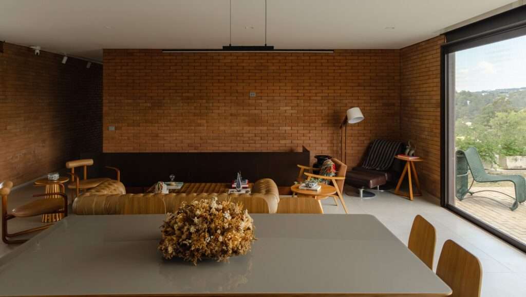 Modern interior design of Casa Plateau's living room featuring exposed brick walls and large glass openings.