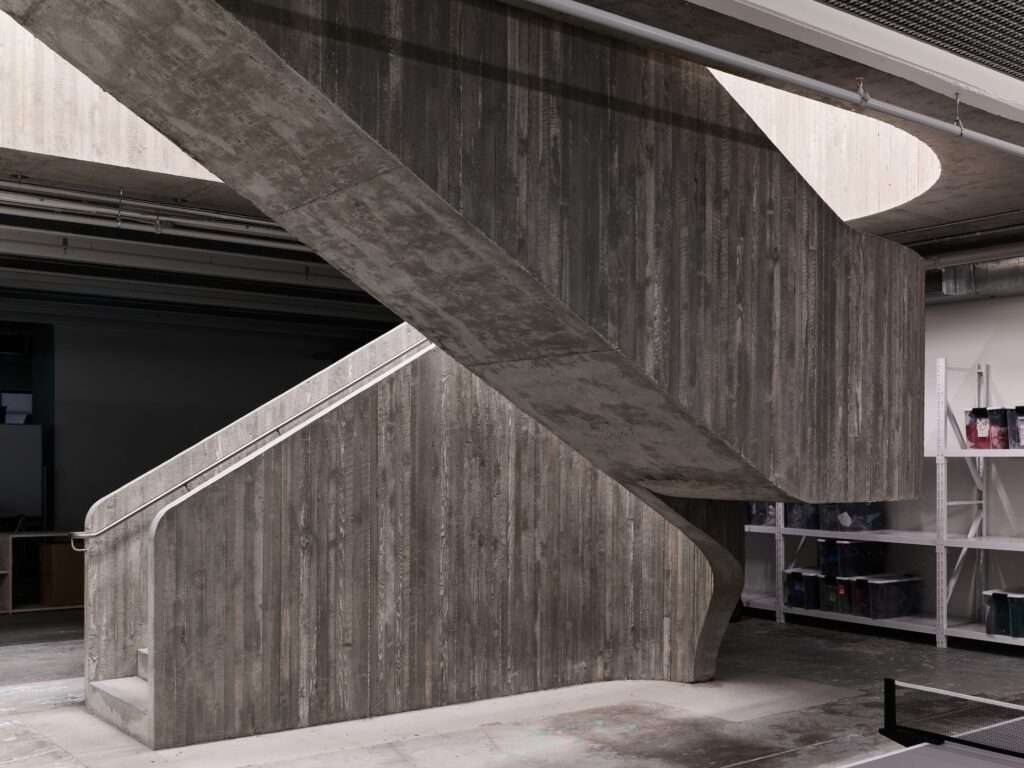 Close-up of the board-formed concrete staircase texture and stainless steel handrails in the Purple Brand warehouse conversion.