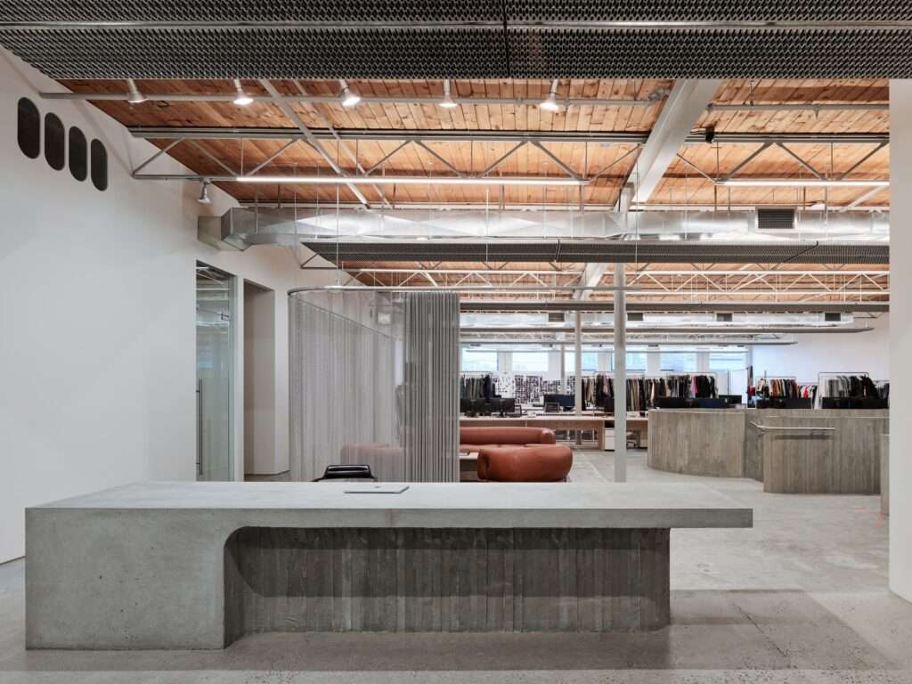 Minimalist concrete reception desk and production workspace at Purple Brand Vancouver, featuring mesh curtains and wooden ceilings.
