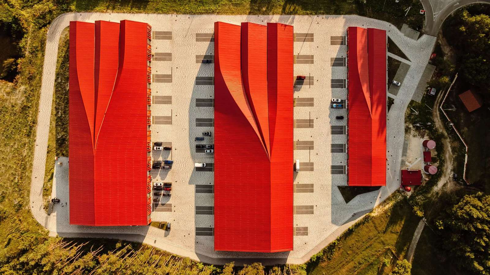 An aerial top-down view of three red-roofed buildings and parking areas.
