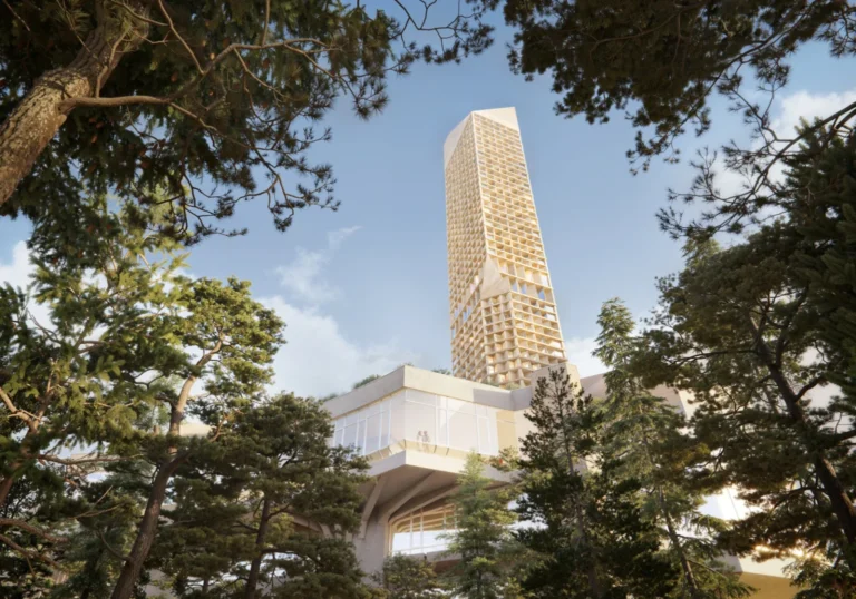 A tall mixed-use tower with a modular grid facade rising above a horizontal podium surrounded by dense trees.