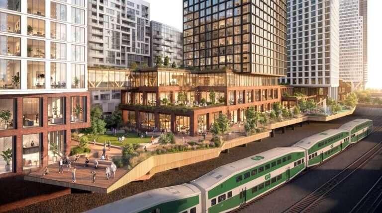 An architectural rendering showing an elevated wood deck and building facade overlooking an active regional train track.
