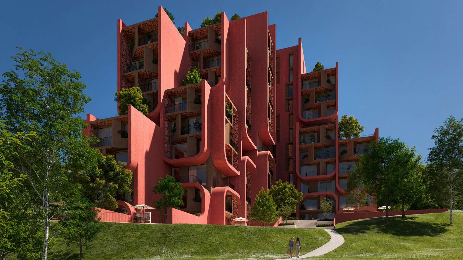 A group of modern residential buildings with deep red curved balconies next to a green lawn.