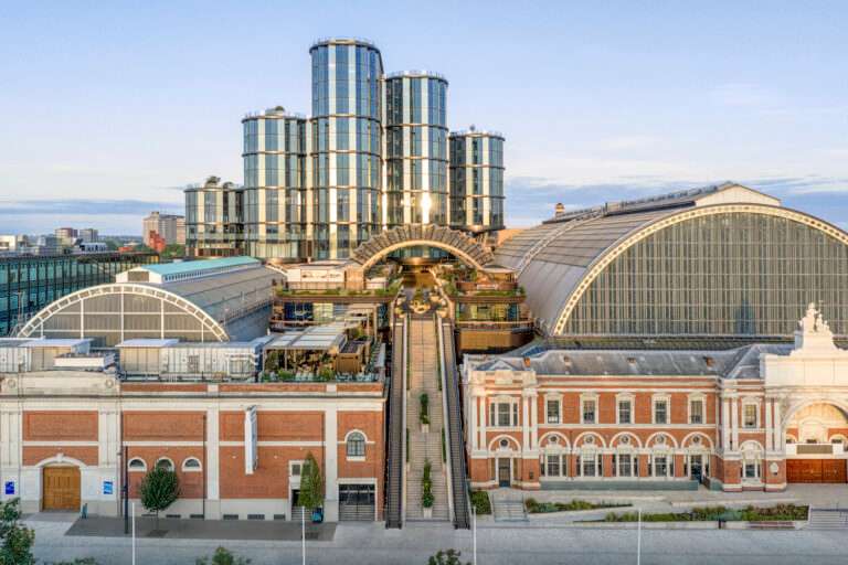 An elevated wide view of the Olympia complex showing historic red brick halls combined with a modern glazed vertical massing.