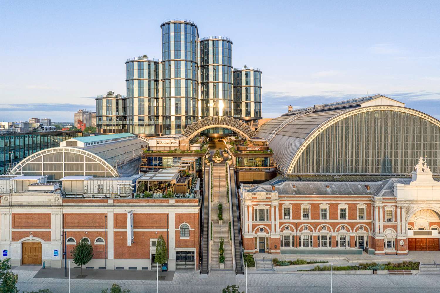An elevated wide view of the Olympia complex showing historic red brick halls combined with a modern glazed vertical massing.