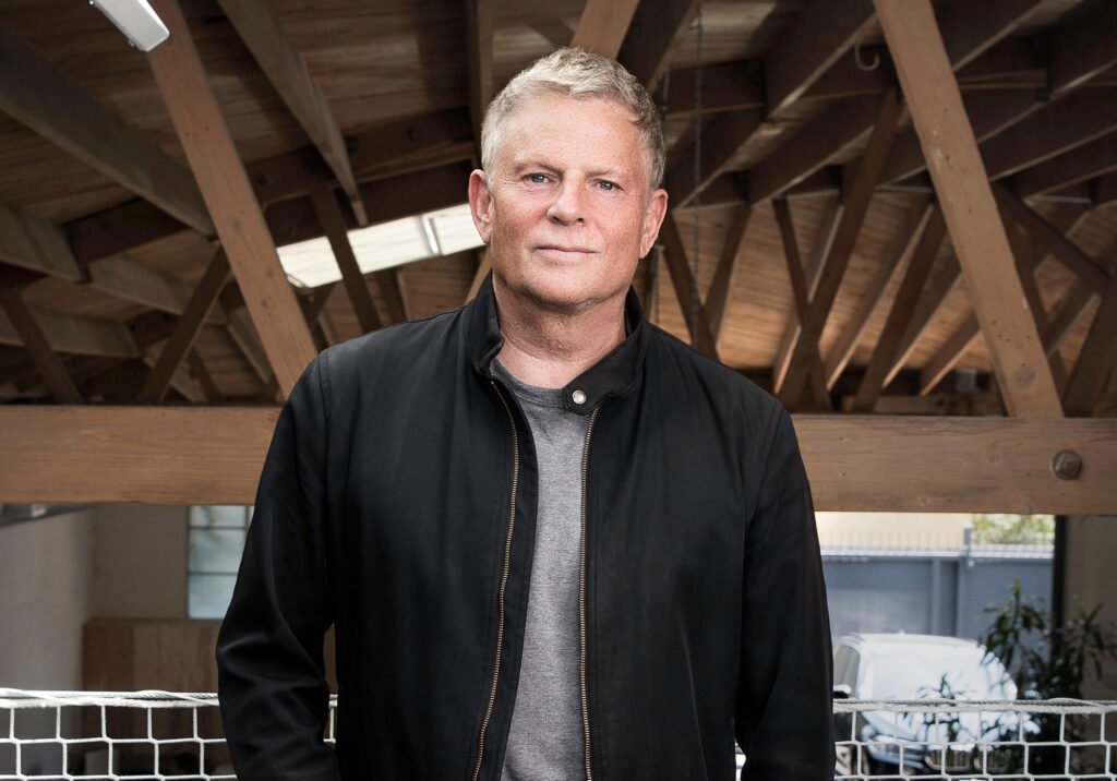 Portrait of architect Lorcan O’Herlihy inside an office with exposed timber roofing.