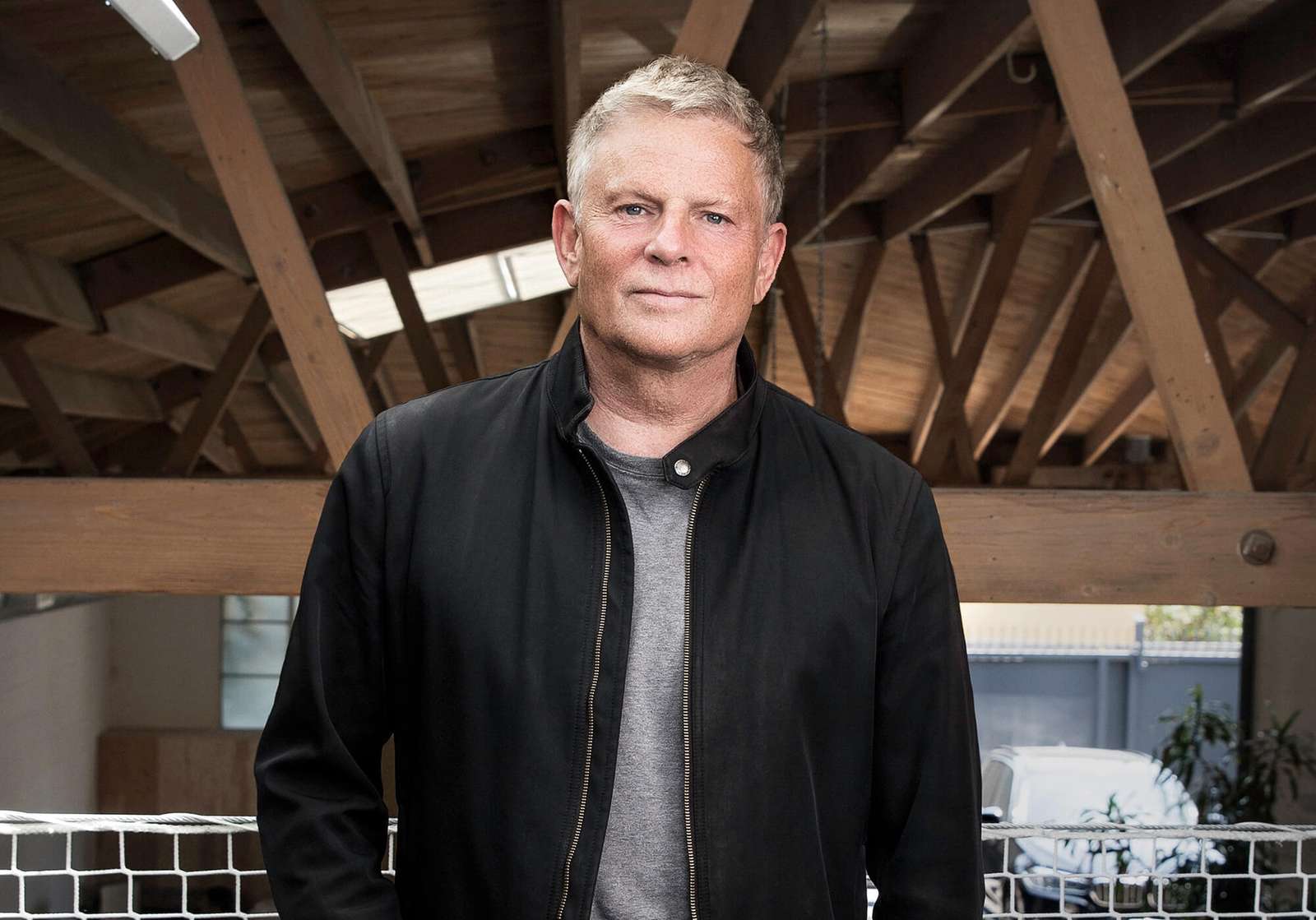Portrait of architect Lorcan O’Herlihy inside an office with exposed timber roofing.
