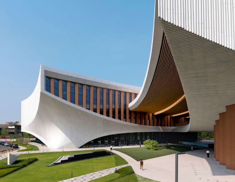 A close-up view of a building facade with a curving white roof canopy above a pedestrian plaza