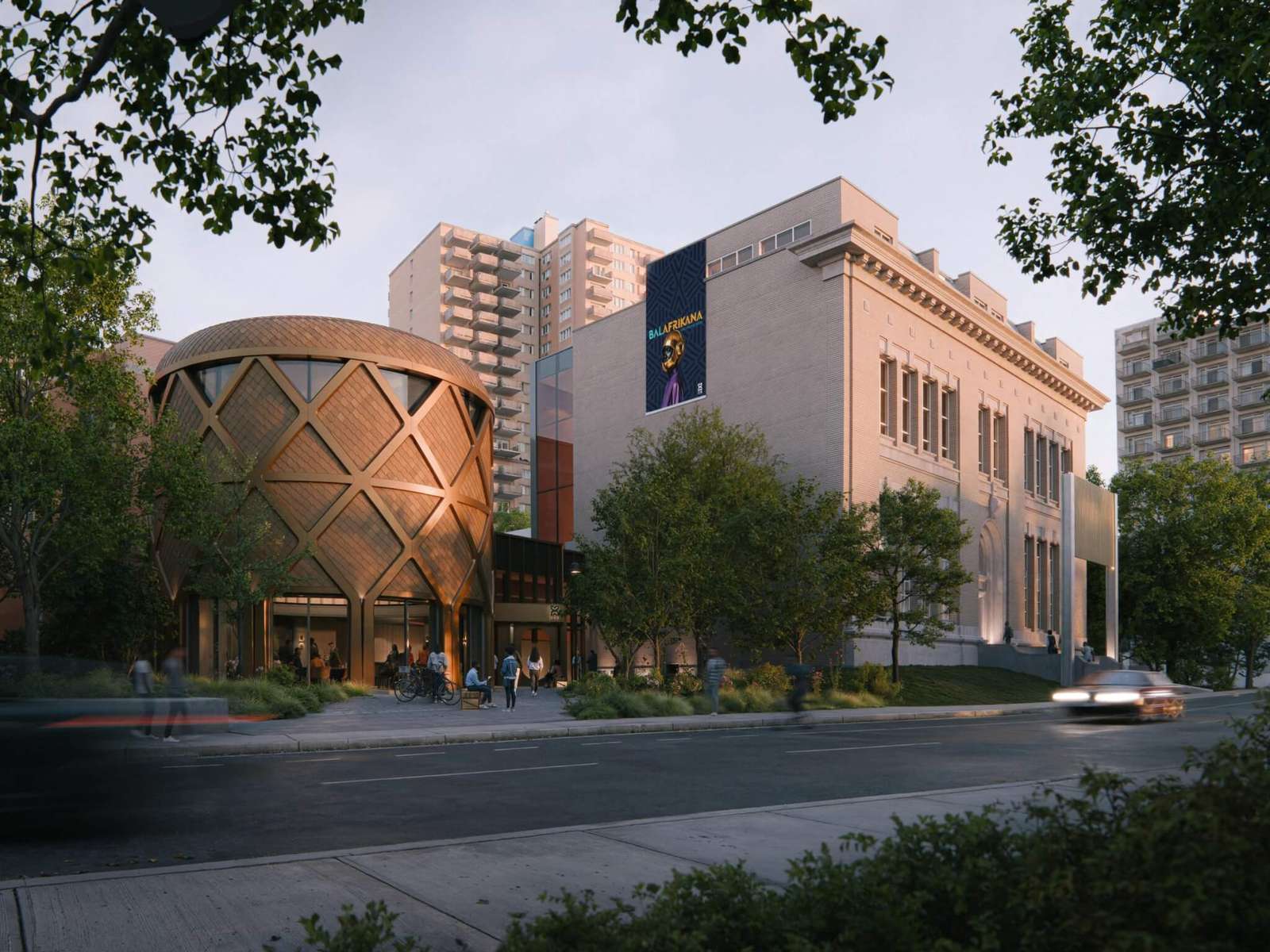 A modern cylindrical drum pavilion with a lattice exoskeleton connected to a historic Beaux-Arts stone building along a street.