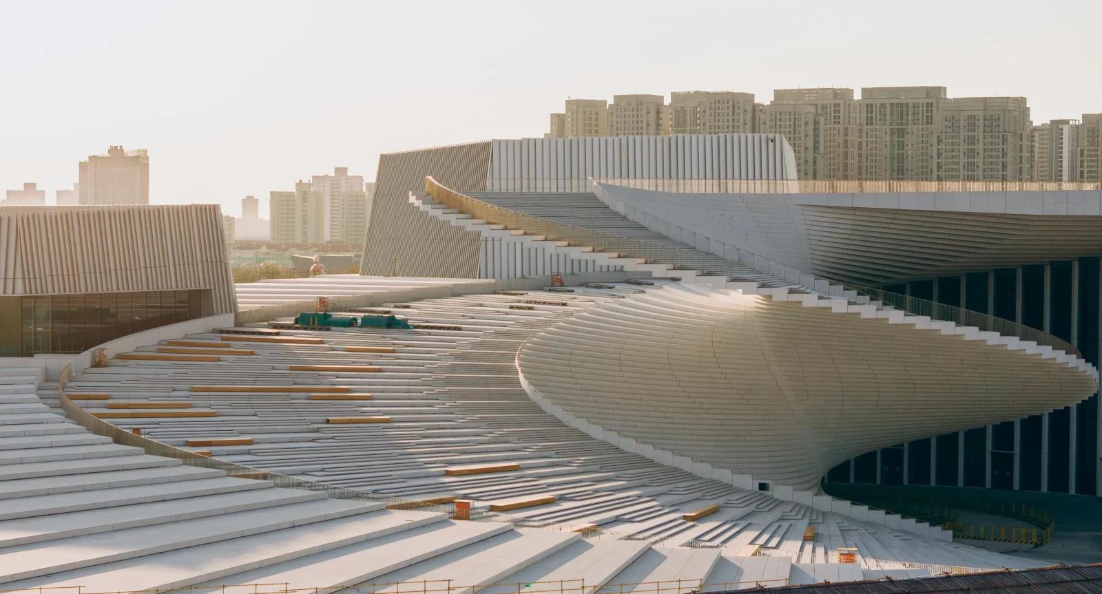 An exterior view of the Shanghai Grand Opera House showing sweeping terraced seating steps and roofscape massing.