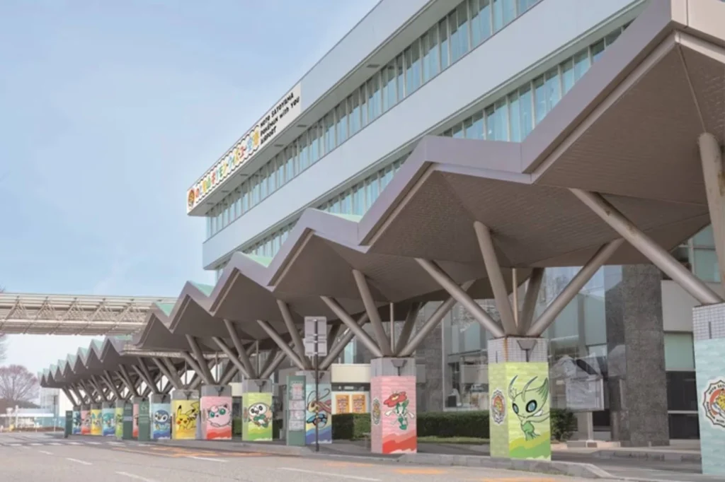Exterior view of an airport terminal building with a prominent multi-bay zig-zag canopy structure.