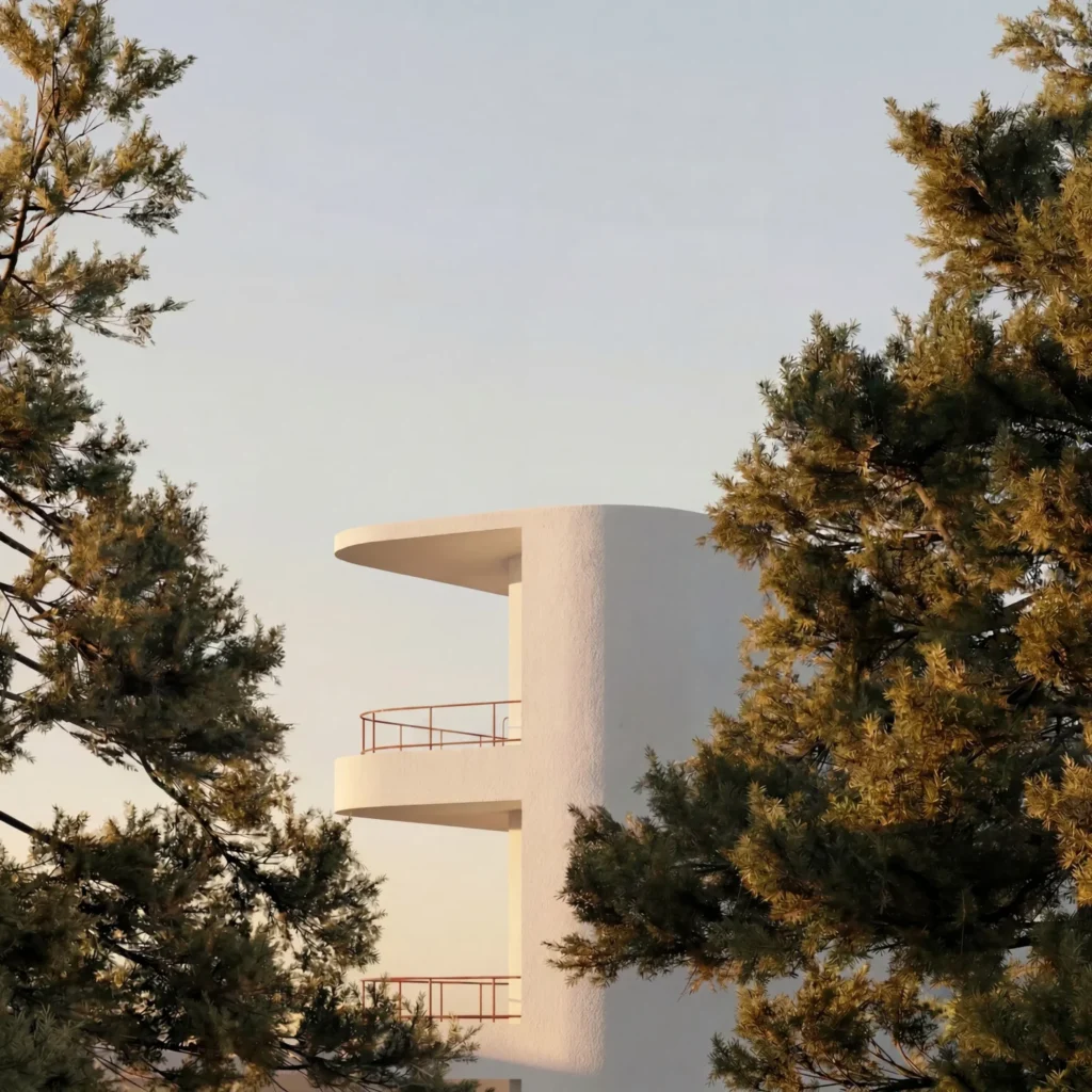 Detail view of white, stacked cantilevered balconies with thin railings framed by green tree branches.