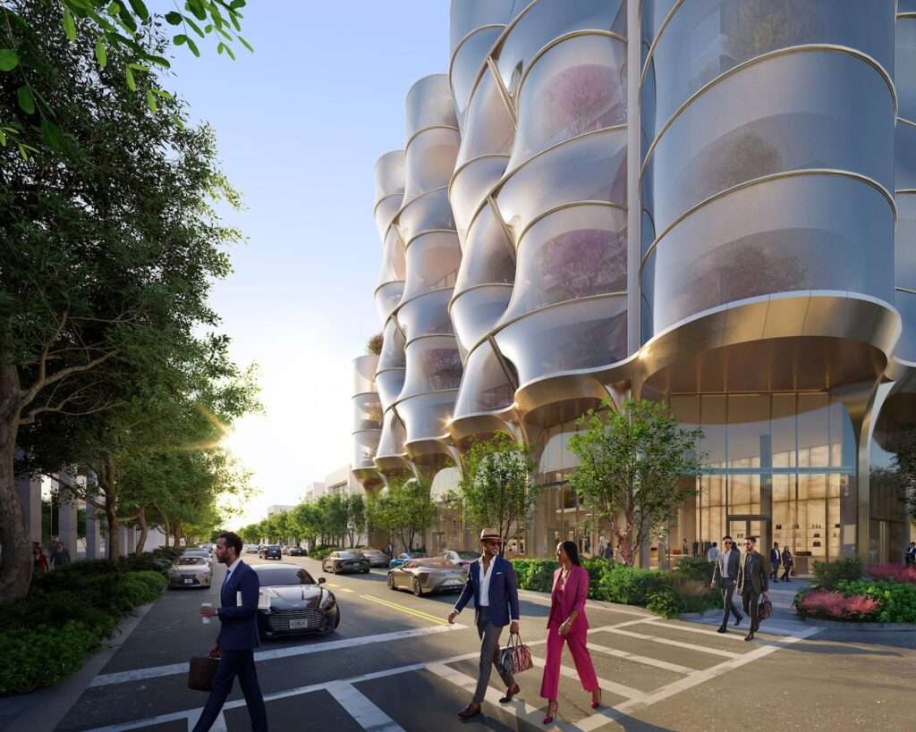 Pedestrians walking along a sidewalk next to a building with a glazed ground floor and metallic columns.