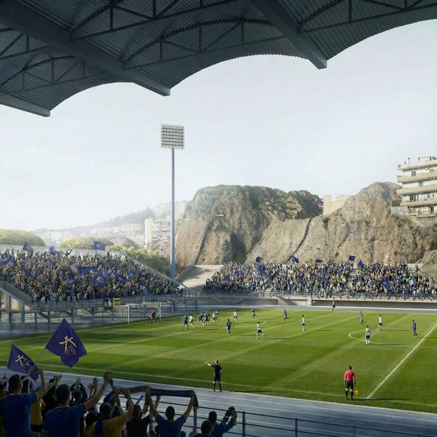 Spectators in seating stands watching a football match next to a steep rocky cliff.