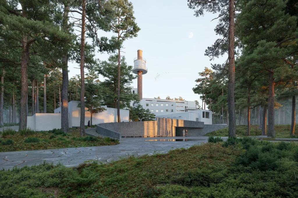 Exterior view from a stone path looking toward a white building facade and a tall industrial brick chimney.