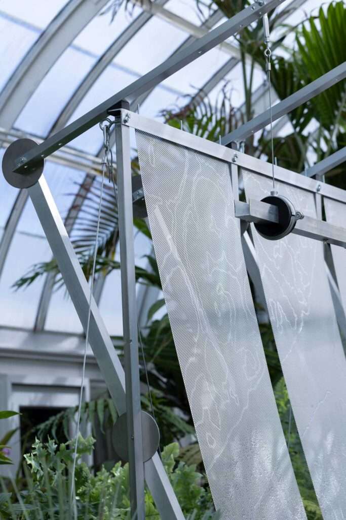 Detail of structural aluminum members, pulleys, turnbuckles, and suspended perforated metal sheets.