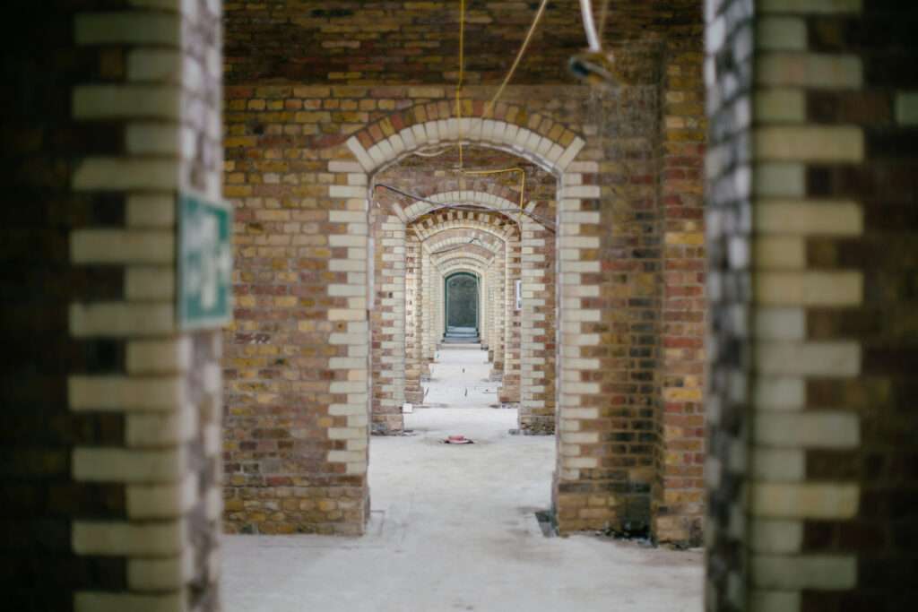 A linear sequence of historic brick arches forming a symmetrical underground circulation route or gallery space.