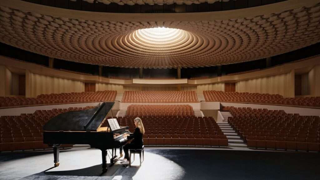 Interior view of an auditorium looking from the stage toward tiered seating under a domed ceiling.