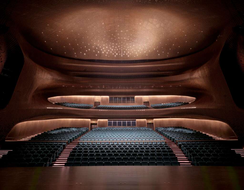 An interior shot looking towards the empty seating tiers and patterned ceiling of a large theatre auditorium