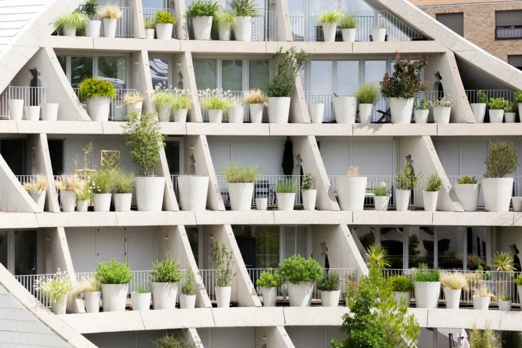 A dense grid-like elevation view of apartment balconies covered with white circular planters and green shrubs.