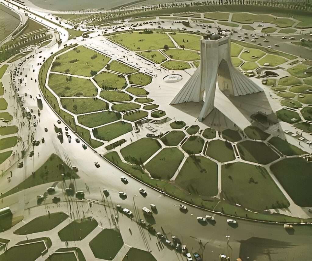 Front view of the white marble-clad Azadi Tower against a clear blue sky, emphasizing its 45-meter height and the structural intersection of Sasanian and Islamic archways.