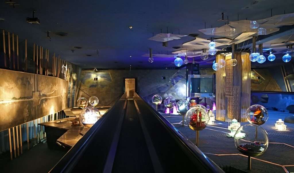 Glass exhibition display cases inside the underground Azadi Museum containing historical artifacts and carved stone sculptures.