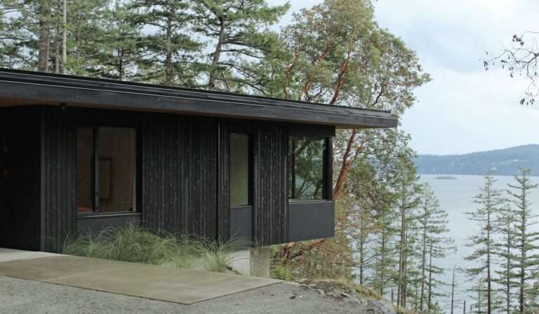 Hilltop House modern coastal residence featuring dark vertical wood cladding and large glass windows overlooking Salish Sea.
