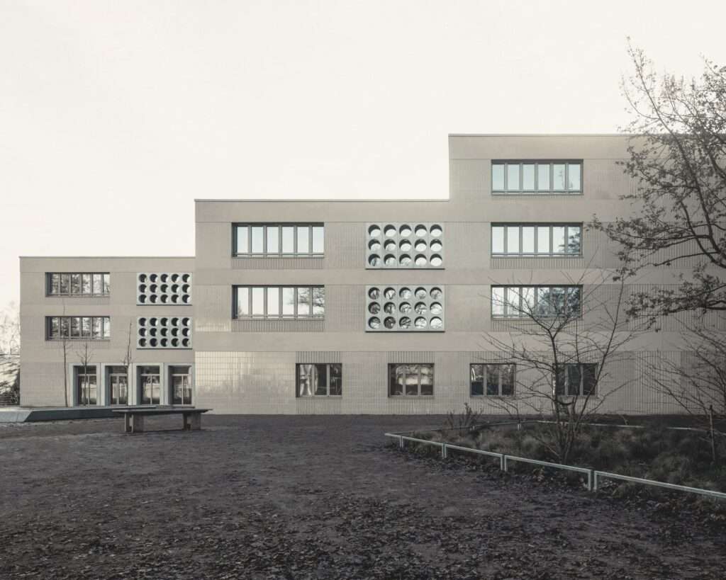 Exterior view of the Lew Tolstoi School extension in Berlin, showing the stepped facade and circular window patterns.