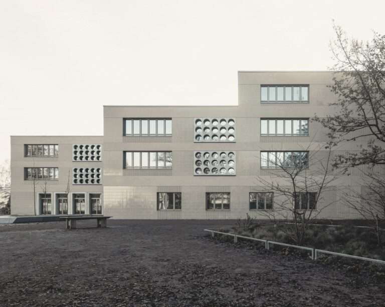 Exterior view of the Lew Tolstoi School extension in Berlin, showing the stepped facade and circular window patterns.