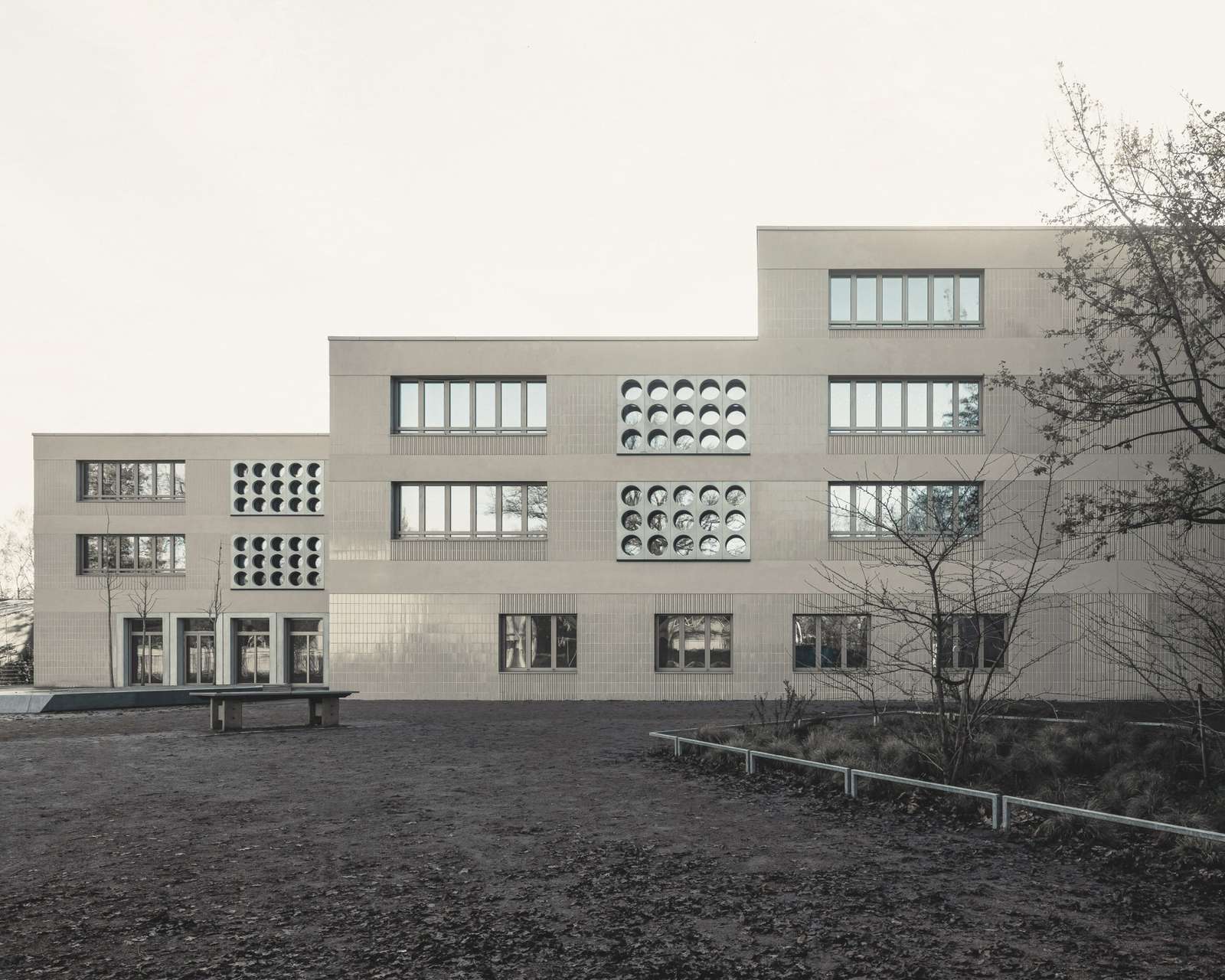 Exterior view of the Lew Tolstoi School extension in Berlin, showing the stepped facade and circular window patterns.