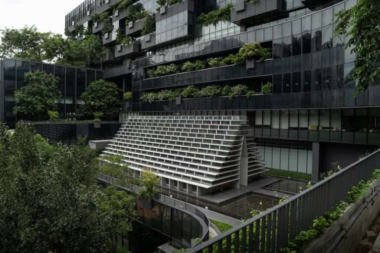 The glass meditation pavilion nestled within a lush garden landscape, reflecting the modern architectural integration with nature.