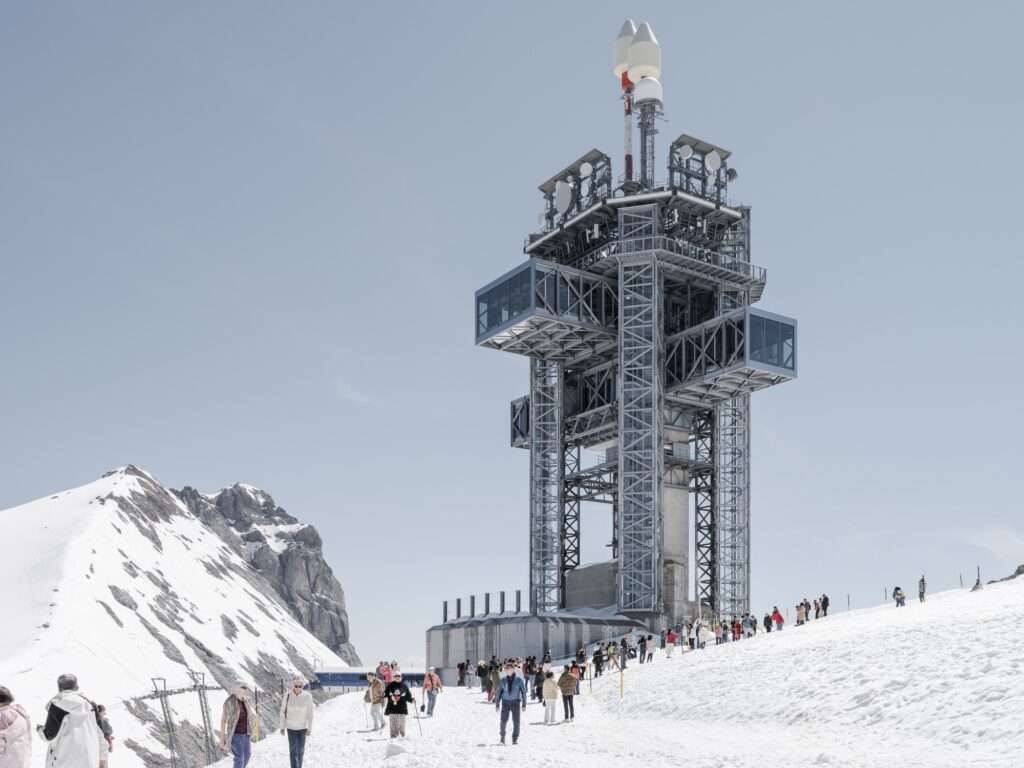 Low-angle shot of tourists walking on a snowy mountain slope toward the retrofitted steel exoskeleton tower on Mount Titlis.