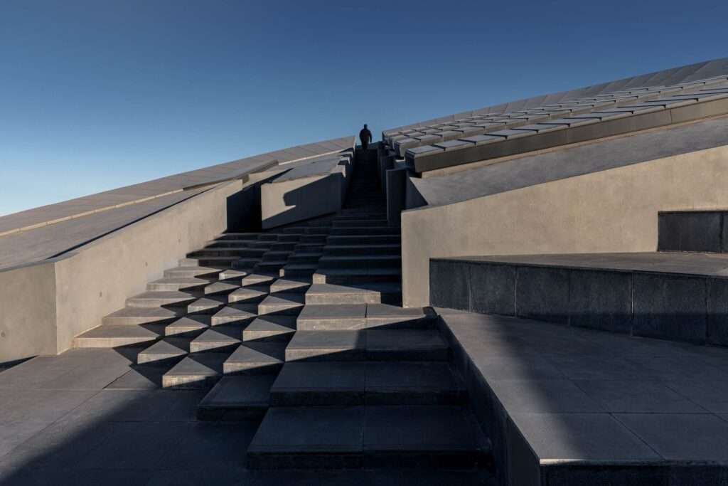 A person walking up the exterior stairs of the Prairie Ark, demonstrating the building's stepped roof integration with the landscape.
