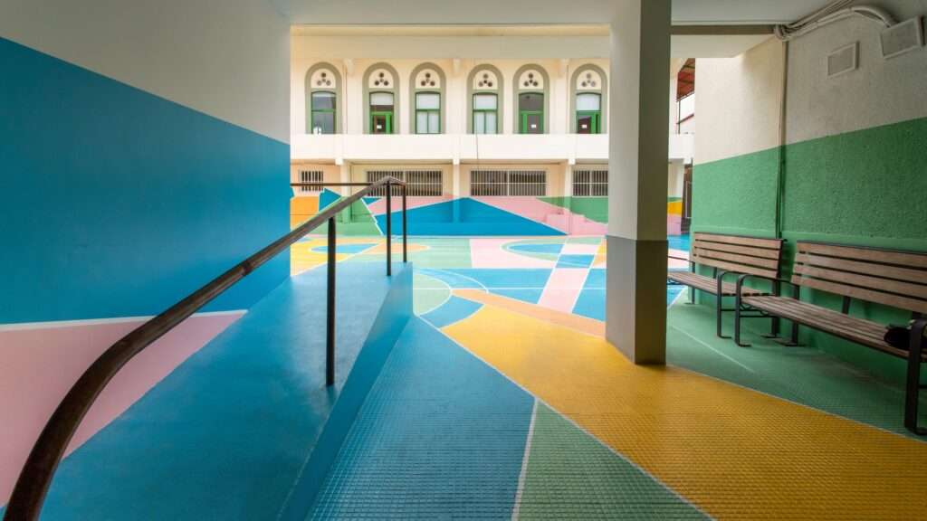 Ground-level view of a vibrant school playground with colorful geometric patterns and benches.