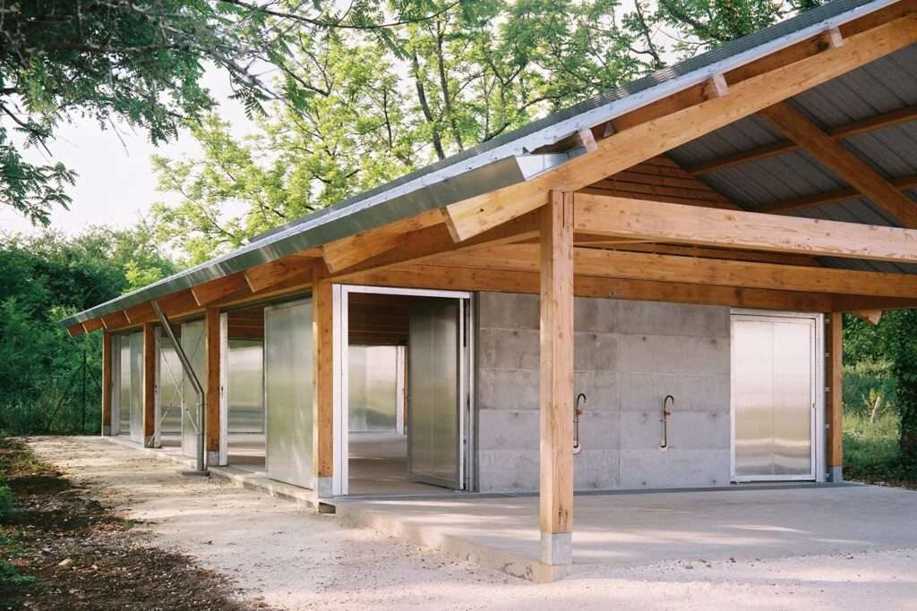 Close-up of the laminated concrete wall with integrated traditional water taps next to translucent sliding polycarbonate panels.