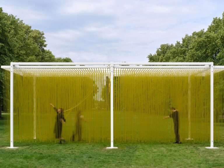 Wide shot of Penetrable BBL Jaune kinetic sculpture by Jesus Rafael Soto at Serpentine Galleries London, showing visitors walking through thousands of hanging yellow PVC tubes inside a white steel frame.
